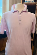 Load image into Gallery viewer, A light pink short-sleeve polo shirt displayed on a cream-colored mannequin torso, set against an indoor background with a window and wooden shelving.