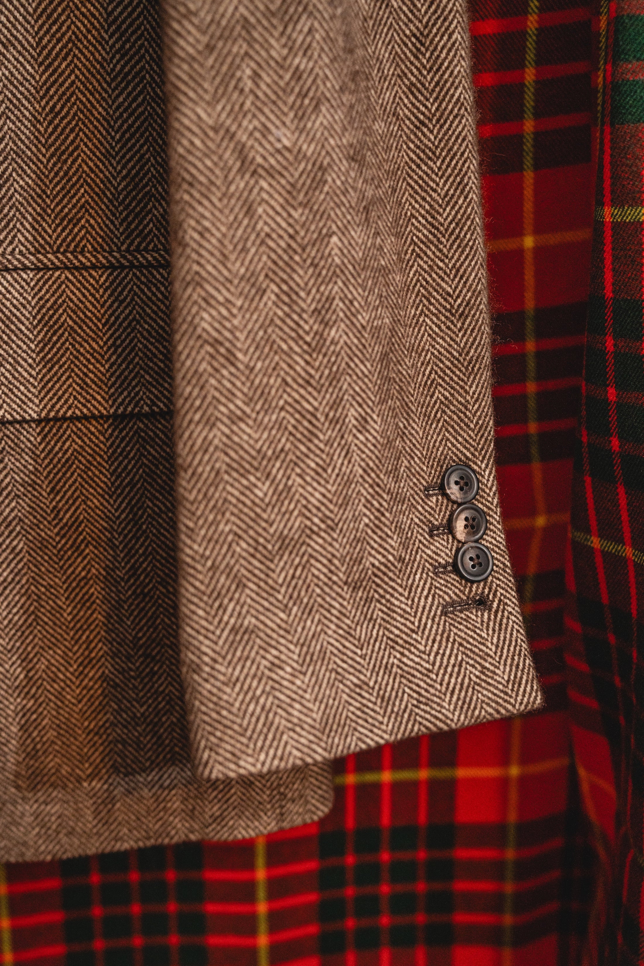 Close-up of textured fabric with a herringbone pattern and a button, alongside a plaid pattern.
